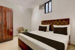 ein Schlafzimmer mit einem großen Bett mit einem hölzernen Kopfteil in der Unterkunft Collection O Sector 7 Dwarka Formerly Aakarshan Residency in Dwarka, New Delhi