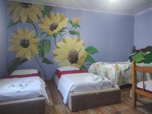 a room with two beds and a mural of flowers on the wall at Pousada Dádiva girassol encantado Pontal Centro in Paraty