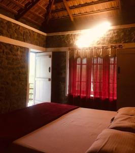 a bedroom with a bed with a red curtain at Jungle retreat waterfalls in Kodaikānāl