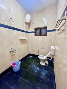 a bathroom with a toilet and a bucket in it at Jungle retreat waterfalls in Kodaikānāl +20 photos