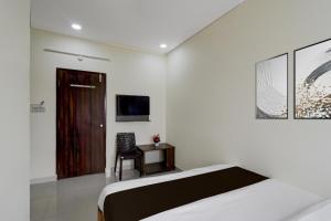 a bedroom with a bed and a desk and a television at Hotel O The Dream Inn in Pedda Ambarpet +22 photos