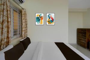 a bedroom with a bed and two paintings on the wall at Hotel O The Dream Inn in Pedda Ambarpet