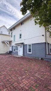 a white house with a brick driveway in front of it at Contemporary Apartment- Prime Location to MBTA in Pawtucket