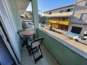 ein Tisch und ein Stuhl auf einem Balkon mit Blick auf eine Straße in der Unterkunft The Férias | Suites Praia in Cabo Frio