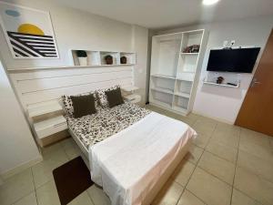 ein kleines Schlafzimmer mit einem Bett und einem Fernseher in der Unterkunft The Férias | Suites Praia in Cabo Frio