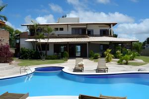 a villa with a swimming pool in front of a house at Casa Bruma |Pé na areia, encontro do rio com o mar in Francês