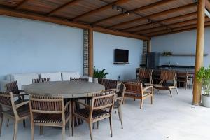 a patio with a table and chairs and a tv at Casa Bruma |Pé na areia, encontro do rio com o mar in Francês
