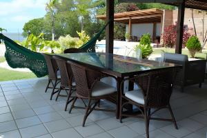 a glass table and chairs on a patio at Casa Bruma |Pé na areia, encontro do rio com o mar in Francês