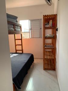 a bedroom with a bunk bed and a book shelf at Aconchego Dutra in Praia Grande