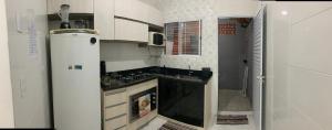 a white kitchen with a stove and a refrigerator at Aconchego Dutra in Praia Grande