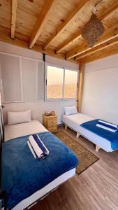 two beds in a room with wooden ceilings at Tourma House in Taghazout