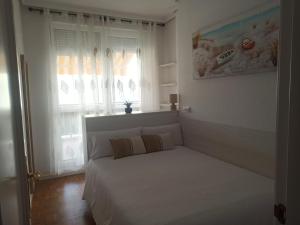a white bed in a room with a window at Apartamento con gran terraza in San Vicente de la Barquera