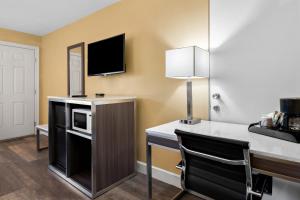 a room with a desk with a microwave and a television at Americas Best Value Inn and Suites Flagstaff in Flagstaff