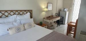 a bedroom with a bed and a desk and a refrigerator at Sufi'Sawd Guest Rooms Muizenberg in Muizenberg