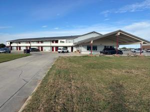 a large white building with a parking lot at Budget Inn Motel in Storm Lake