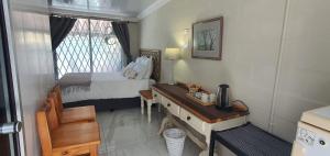 a small room with a bed and a desk with a desk at Sufi'Sawd Guest Rooms Muizenberg in Muizenberg
