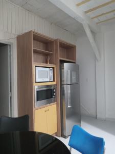 a kitchen with a microwave and a refrigerator at Casa aconchegante próxima a praia in Laguna