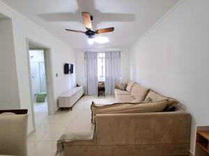 un salon avec un canapé et un ventilateur de plafond dans l'établissement Apartamento com Suite Praia da Enseada Dois Quartos, à Guarujá