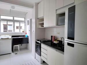 une cuisine avec des armoires blanches et un comptoir noir dans l'établissement Apartamento com Suite Praia da Enseada Dois Quartos, à Guarujá