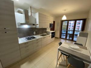 a kitchen with white cabinets and a table and a dining room at The Prince's Nest in Potenza