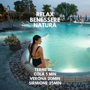 a woman sitting in front of a swimming pool at Studio Centrale Pacengo di Lazise in Lazise