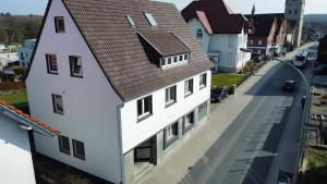 a white building with a brown roof on a street at Apartment mit 2 Betten in Flughafennähe in Paderborn