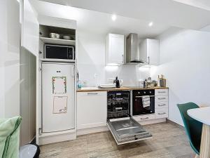 a kitchen with white cabinets and a white refrigerator at Maisonnette 36m2 à 5 minutes de Chantilly in Vineuil-Saint-Firmin