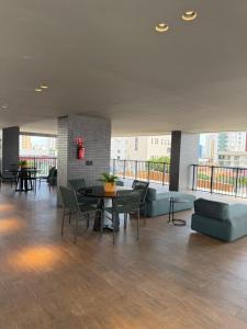 a lobby with a couch and tables and chairs at Loft Urbano in João Pessoa