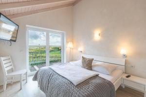 a white bedroom with a bed and a window at Schimmelreiter in Struckum