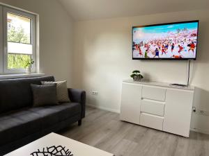 a living room with a couch and a flat screen tv on the wall at FeWo Panorama in Diemelsee