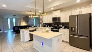 a kitchen with white cabinets and a black refrigerator at Stay Our Stylish 2 Br, 6 Minutes To Disney World in Kissimmee