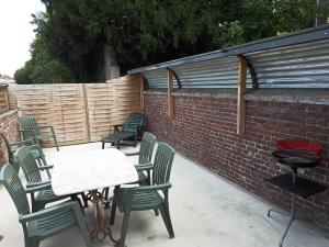 a patio with chairs and tables and a brick wall at Maisonnée au cœur de la Thierache 