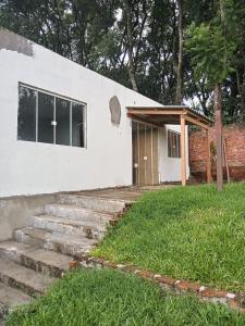 a white building with a wooden door and some grass at A home away from home in Ijuí