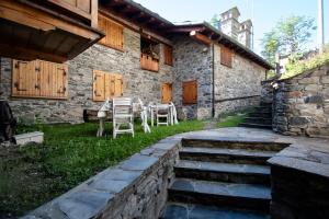 a stone house with chairs and a table in the yard at Case Gran Paradiso Rhemes Notre Dame Carré in Rhêmes-Notre-Dame