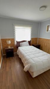 a bedroom with a large white bed and a window at Cabañas dunn in Puerto Cisnes