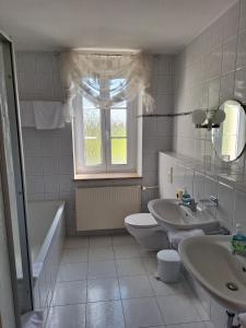 a bathroom with two sinks and a toilet and a tub at Hotel Heilbrunnen in Jöhstadt +75 photos