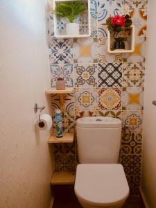 a bathroom with a toilet and a tiled wall at L'oasis, appartement proche plage privée in Grand-Bourg +21 photos