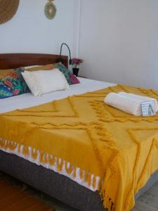 a bed with a yellow blanket on top of it at L'oasis, appartement proche plage privée in Grand-Bourg