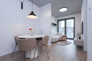 a white dining room with a table and chairs at Metropolis- brand new apartment with free parking in Nivy