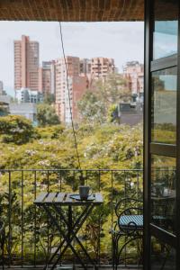 einen Tisch und Stühle auf einem Balkon mit Stadtblick in der Unterkunft Hotel dieztreintayseis in Medellín
