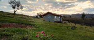 a small house on top of a grassy hill at Refúgio na Serra dos Garcias in Aiuruoca