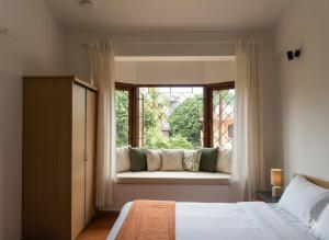 a bedroom with a bed and a window with a couch at Navilehomestay in Candolim
