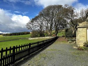 a fence in front of a field and trees at The Bronte Moor Retreat - 3 Bed, Pet Friendly Cottage - Stunning Views - Hot Tub in Heptonstall