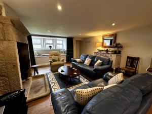 a living room with a leather couch and a fireplace at The Bronte Moor Retreat - 3 Bed, Pet Friendly Cottage - Stunning Views - Hot Tub in Heptonstall +41 photos