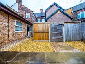 ストーク・オン・トレントにあるEn-suite 2 Woodhouse, private bath, 2 kitchenの木の門と葉っぱの山がある家