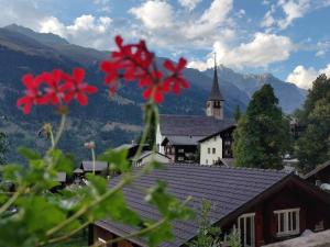une fleur rouge devant un bâtiment avec une église dans l'établissement Ferienwohnung Aragon M88, à Ernen