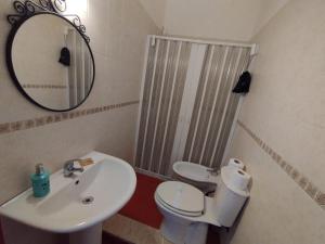 een badkamer met een wastafel, een toilet en een spiegel bij GiGi Affittacamere in Siracusa