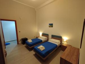 twee bedden in een kleine kamer met blauwe lakens bij GiGi Affittacamere in Siracusa