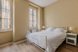 a bedroom with a white bed and two windows at Un T3 à 2 petits pas in Bagnères-de-Bigorre