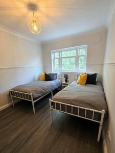 two beds in a room with a window at Stunning 3Bed 2bath family home with Garden in London